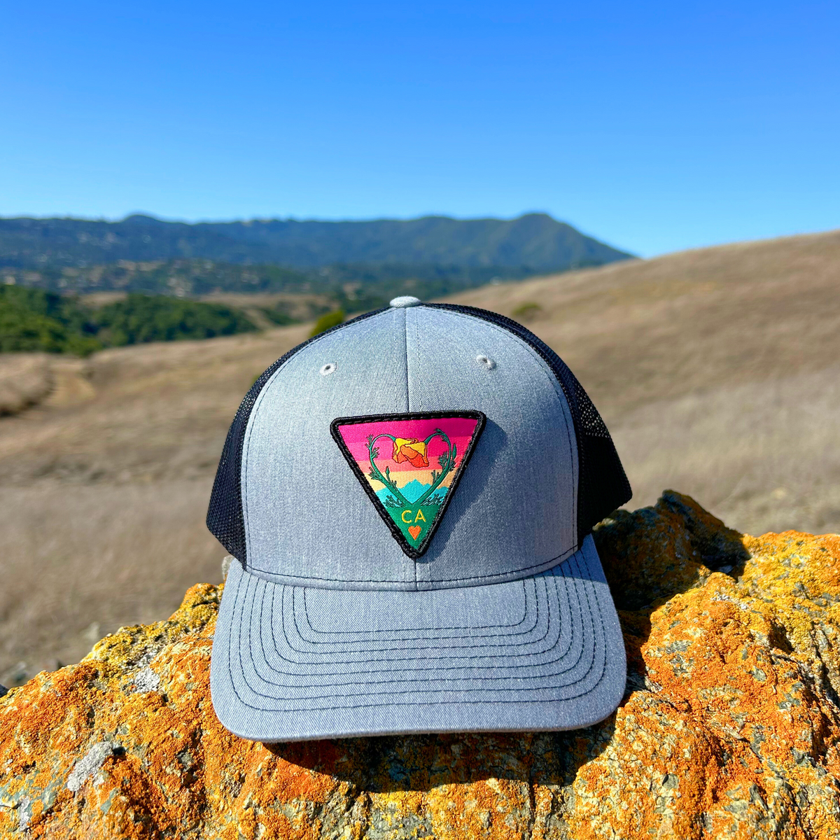 Heather grey and black Kooh Culture trucker hat with the Poppy CA Love patch