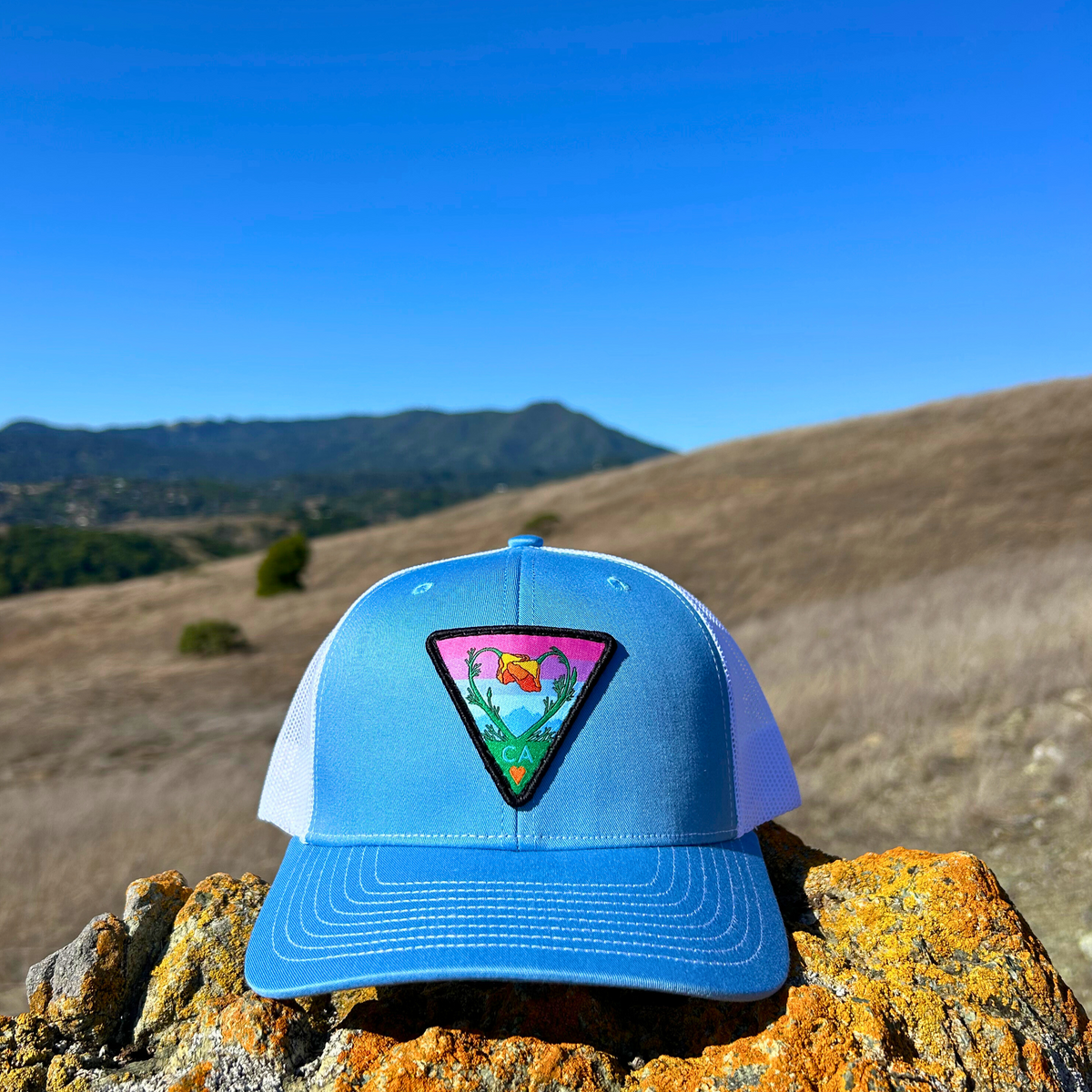 Light blue and white Kooh Culture trucker hat with the Poppy CA Love patch