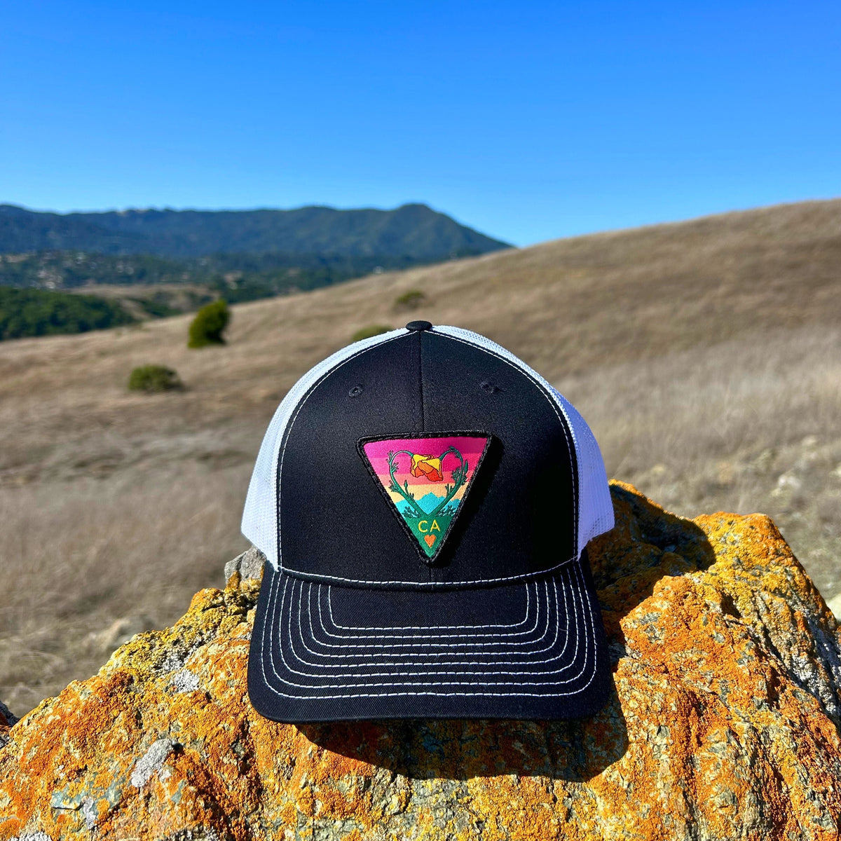 Black and white Kooh Culture trucker hat with the Poppy CA Love patch