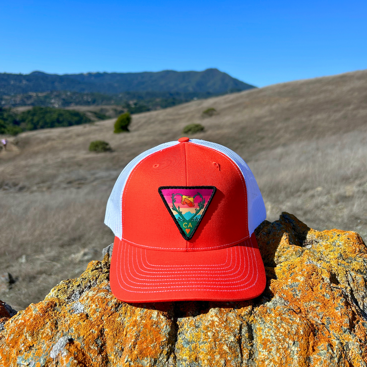 Bright orange and white Kooh Culture trucker hat with the Poppy CA Love patch