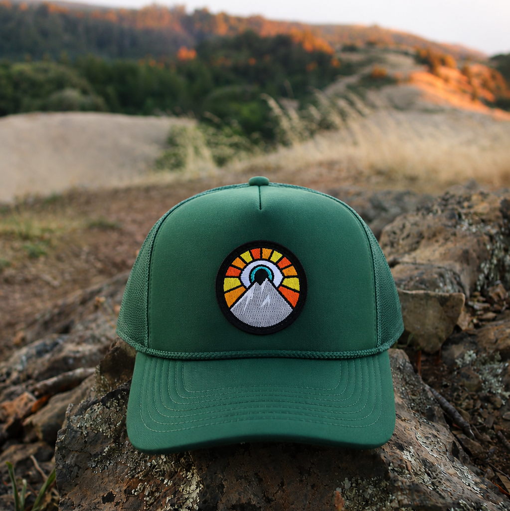 Dark green Kooh Culture trucker hat with the Evil Eye Sun patch