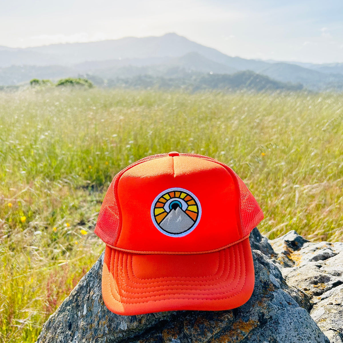 Orange Kooh Culture foam trucker hat with the Evil Eye Sun patch