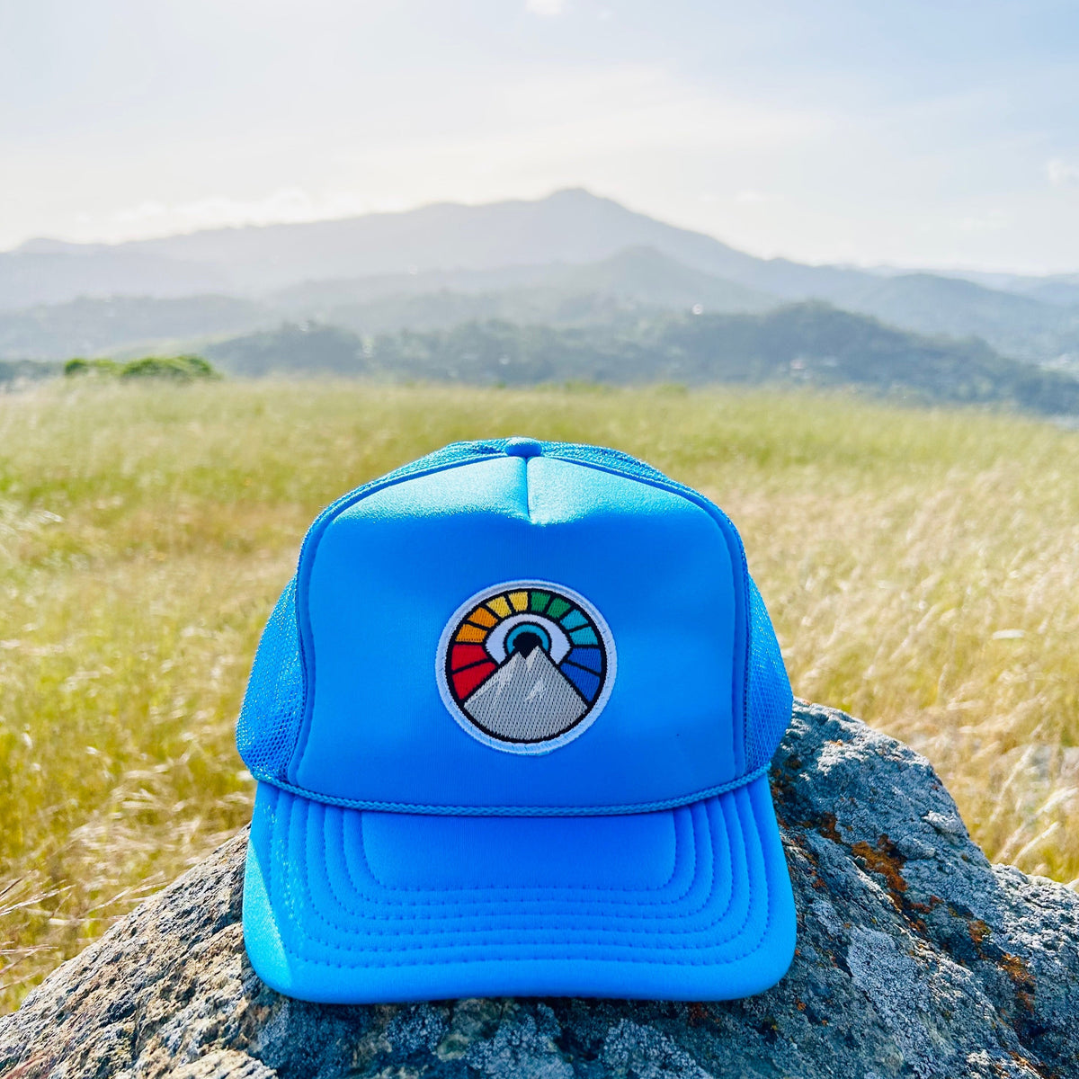 Neon blue Kooh Culture foam trucker hat with the Evil Eye Sun patch in Rainbow Edition colours