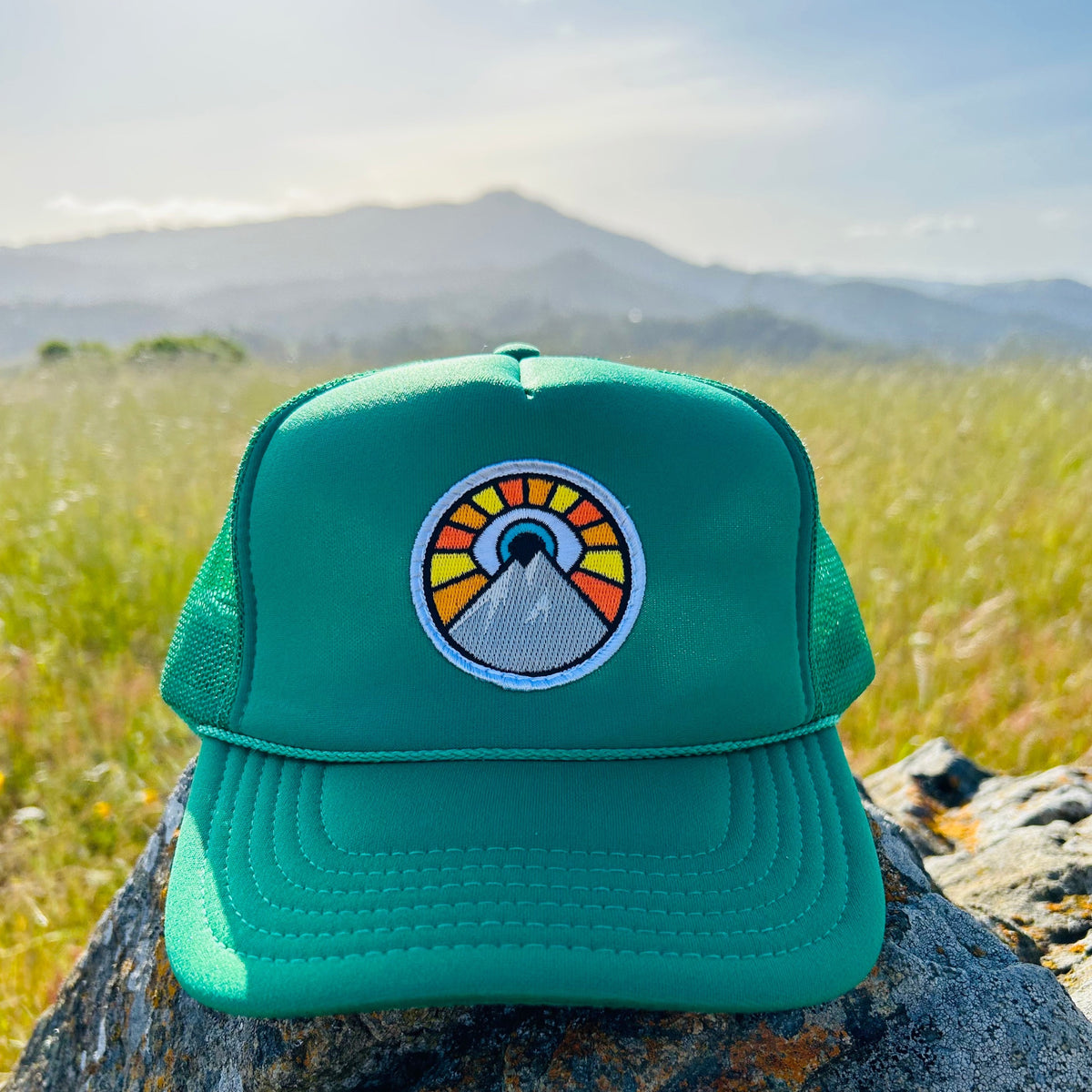 Kelly green Kooh Culture foam trucker hat with the Evil Eye Sun patch
