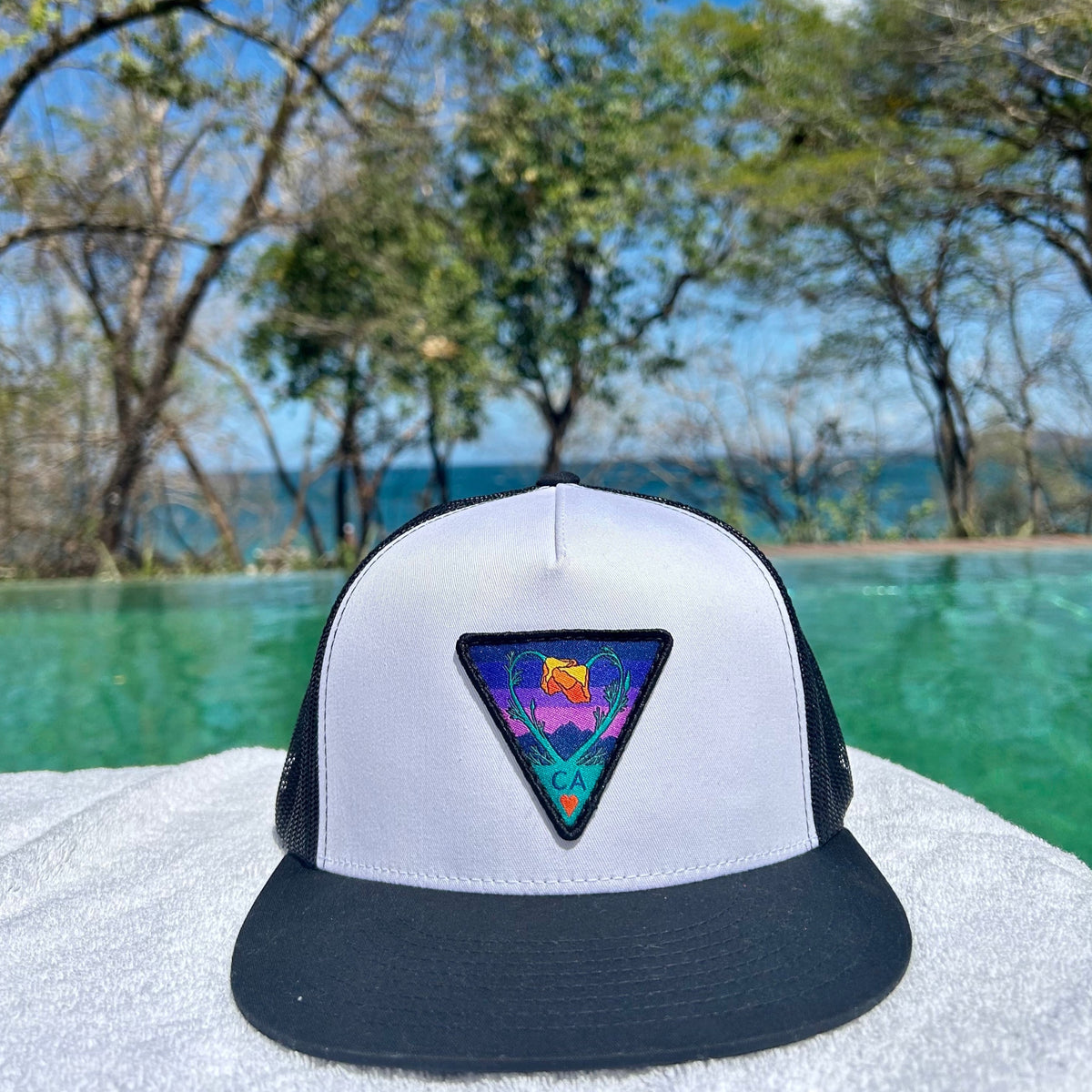 White and black Kooh Culture flat brim trucker hat with the Poppy CA Love patch in Night Mode colours