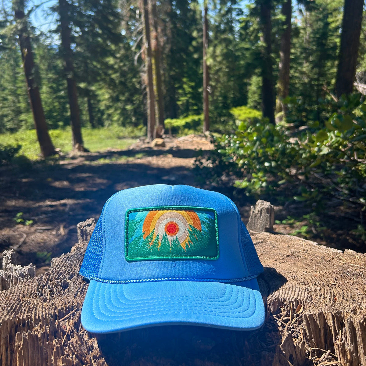 Light blue Kooh Culture foam trucker hat with the In the Trees XL patch