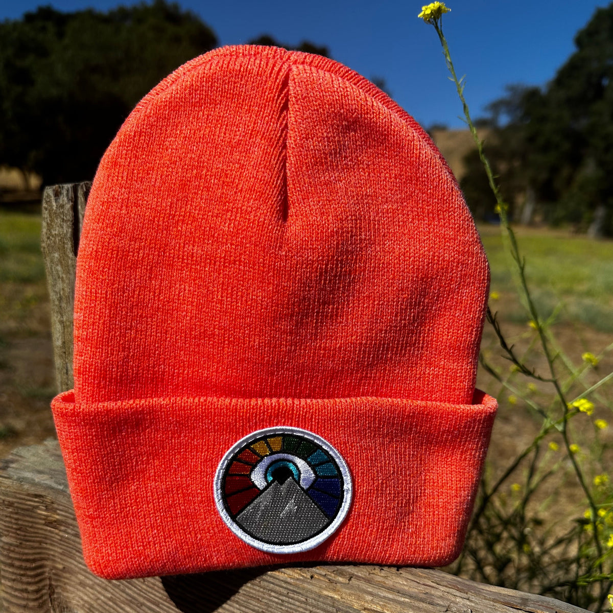 Neon orange Kooh Culture cuffed beanie with the Evil Eye Sun patch in Rainbow Edition colours