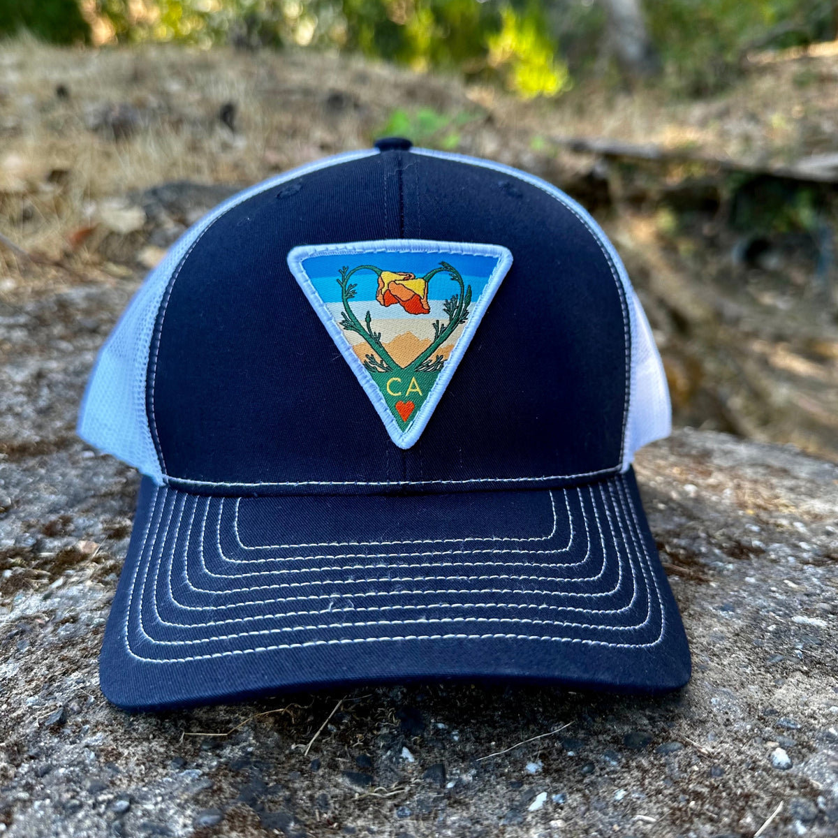 Navy and white Kooh Culture trucker hat with the Poppy CA Love patch