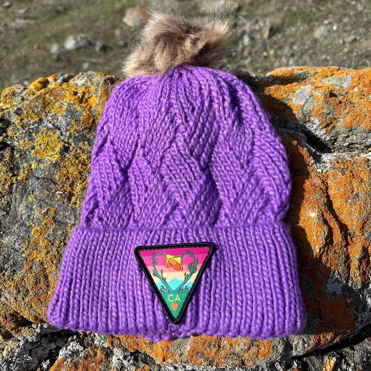 Purple Kooh Culture cable knit pom beanie with the Poppy CA Love patch