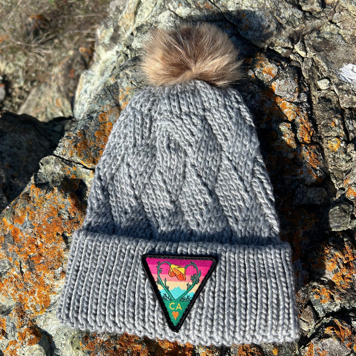 Grey Kooh Culture cable knit pom beanie with the Poppy CA Love patch