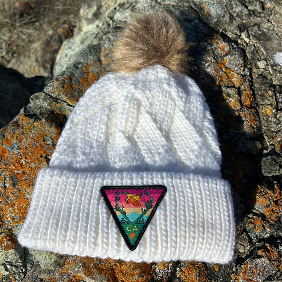 White Kooh Culture cable knit pom beanie with the Poppy CA Love patch