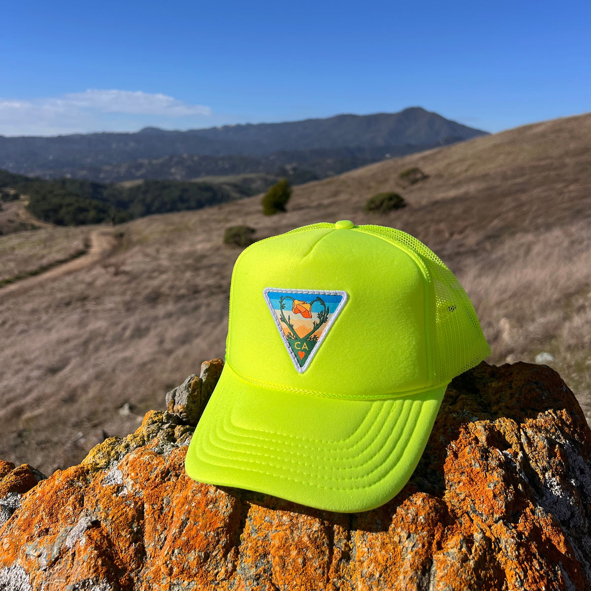 Neon yellow Kooh Culture foam trucker hat with the Poppy CA Love patch