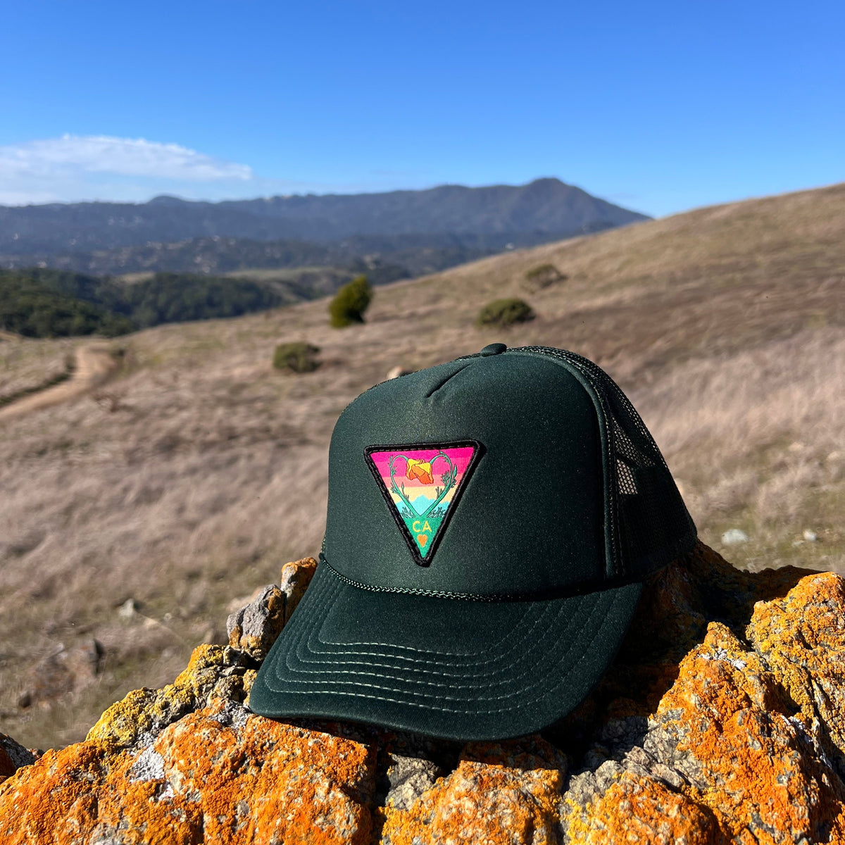 Dark green Kooh Culture foam trucker hat with the Poppy CA Love patch