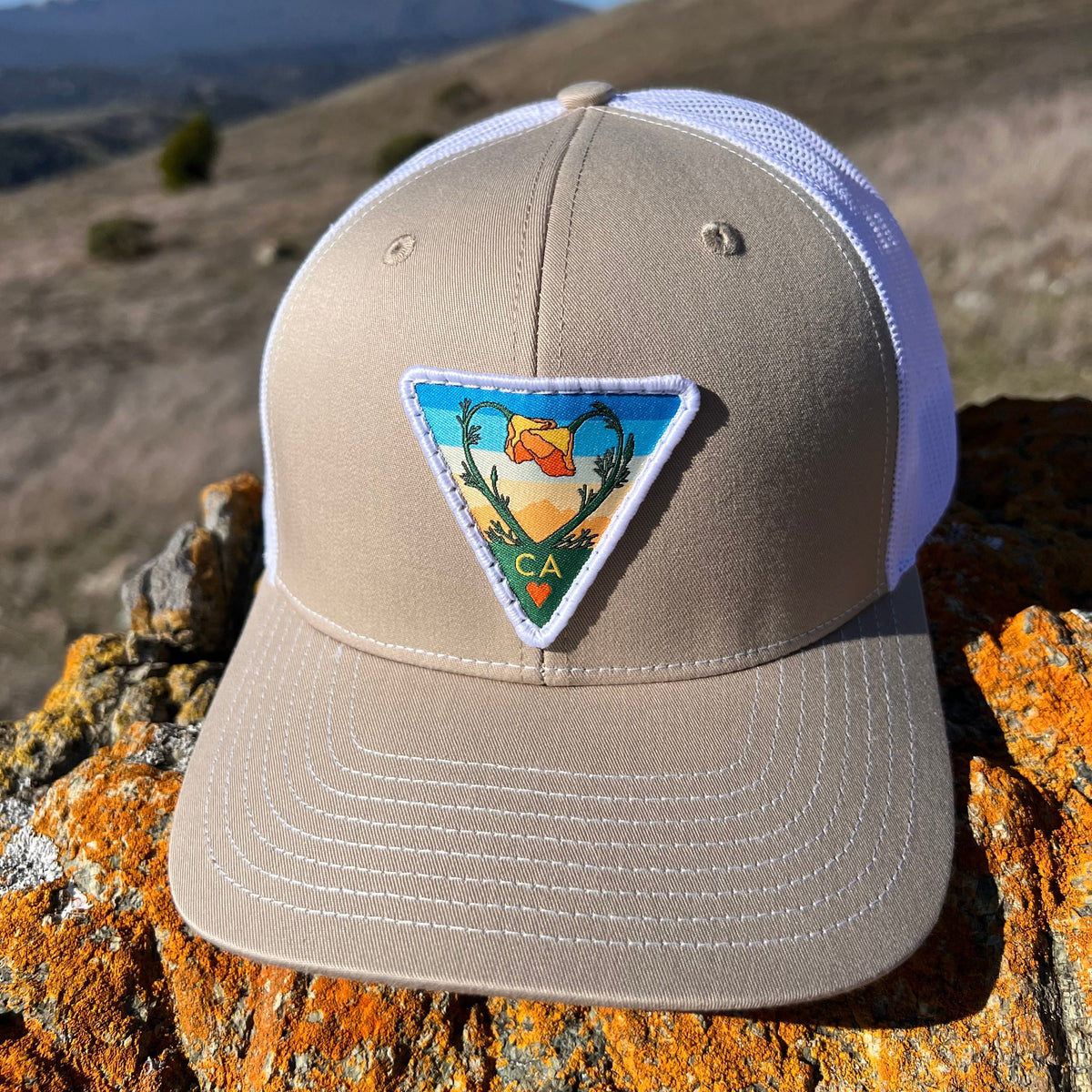 Khaki and white Kooh Culture trucker hat with the Poppy CA Love patch