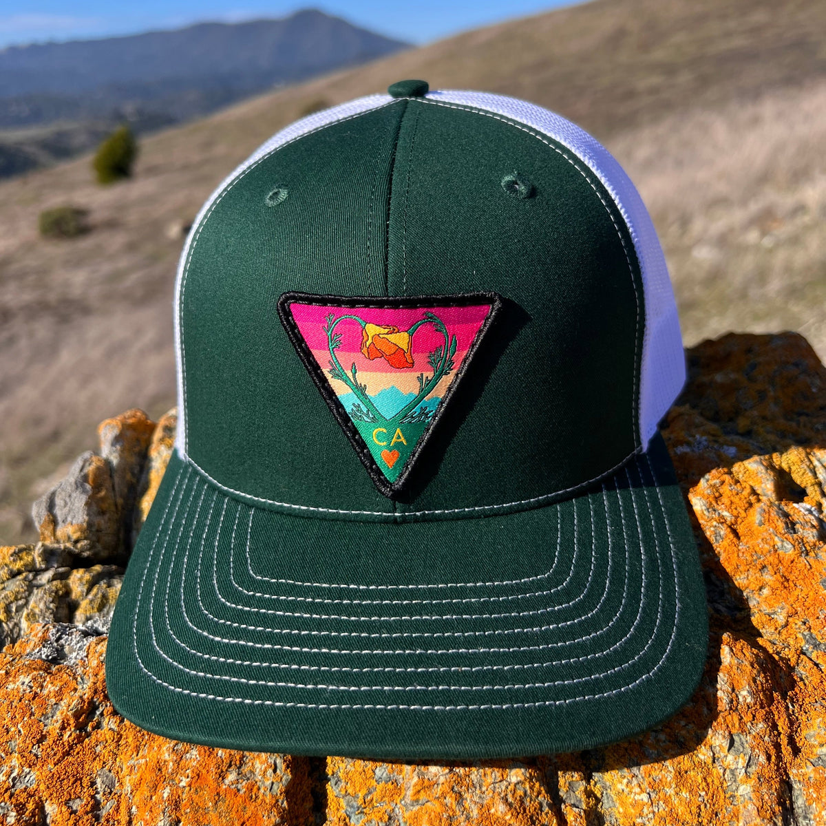 Dark green and white Kooh Culture trucker hat with the Poppy CA Love patch