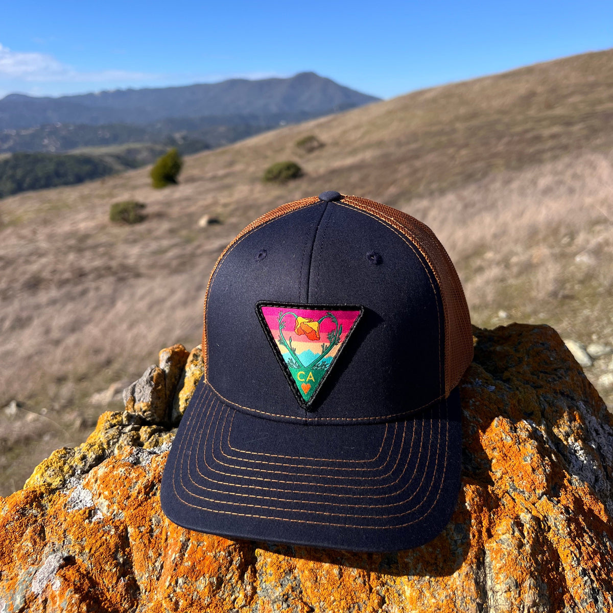 Navy and caramel Kooh Culture trucker hat with the Poppy CA Love patch