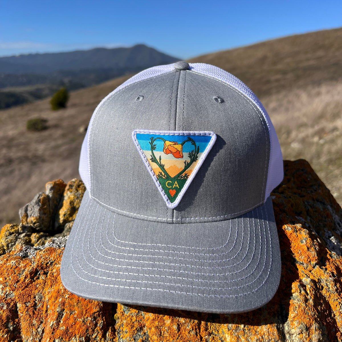 Heather grey and white Kooh Culture trucker hat with the Poppy CA Love patch