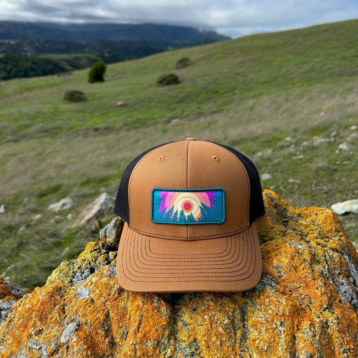 Caramel and black Kooh Culture trucker hat with the In the Trees patch