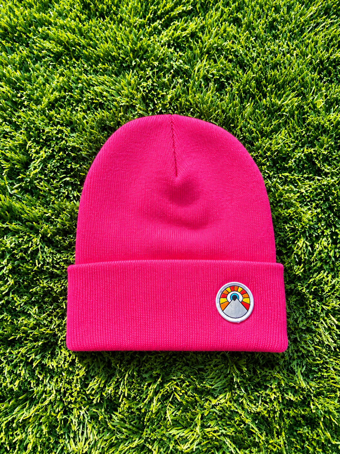 Hot pink Kooh Culture cuffed beanie with the Evil Eye Sun patch
