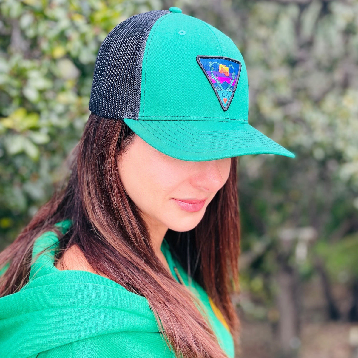 Kelly green and black Kooh Culture trucker hat with the Poppy CA Love patch in Night Mode colours