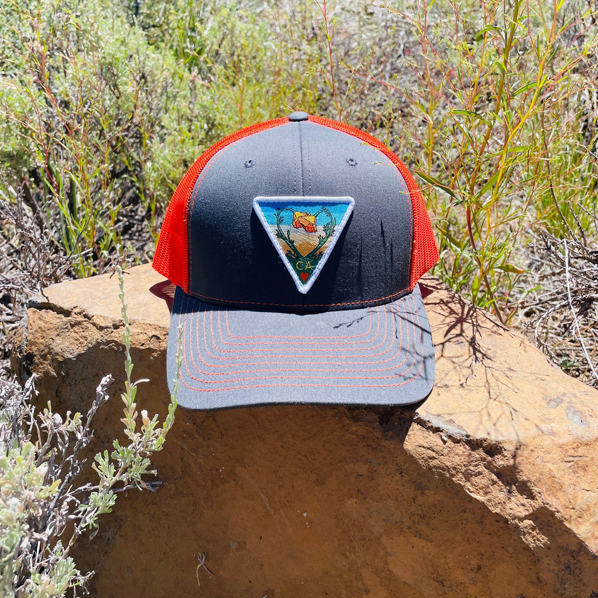 Grey and neon orange Kooh Culture trucker hat with the Poppy CA Love patch