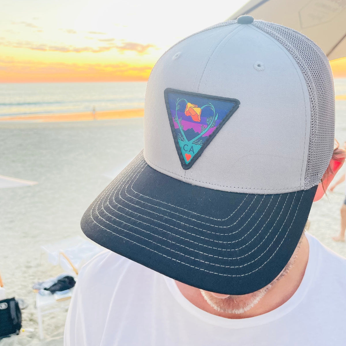 Grey and charcoal and black Kooh Culture trucker hat with the Poppy CA Love patch in Night Mode colours, alternate view